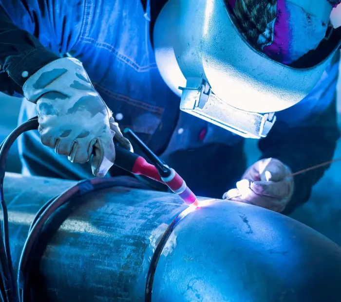 A person welding metal with a pair of gloves.