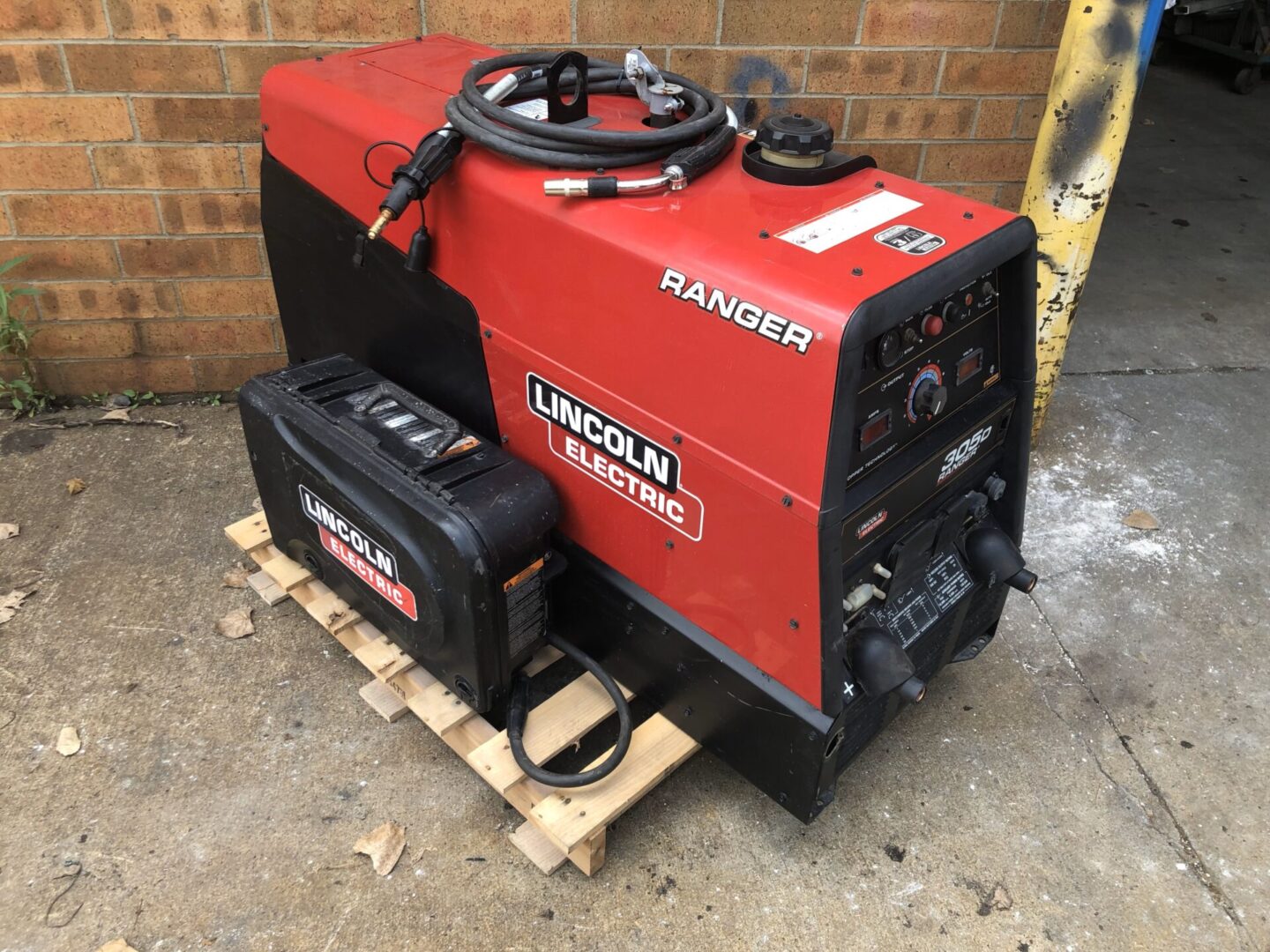 A red and black machine sitting on top of a wooden pallet.