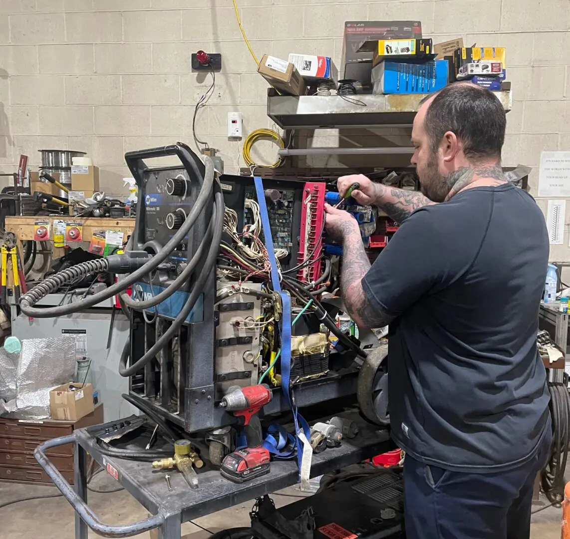 A man working on an electrical device in a workshop.